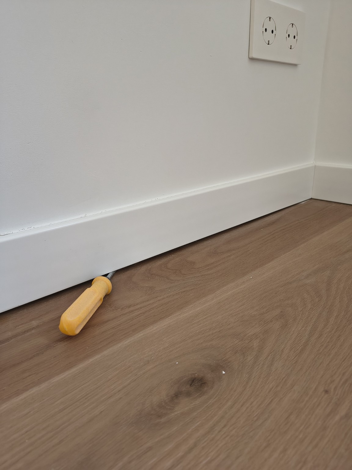 Close-up of the gap beneath the skirting, indicated with a tool